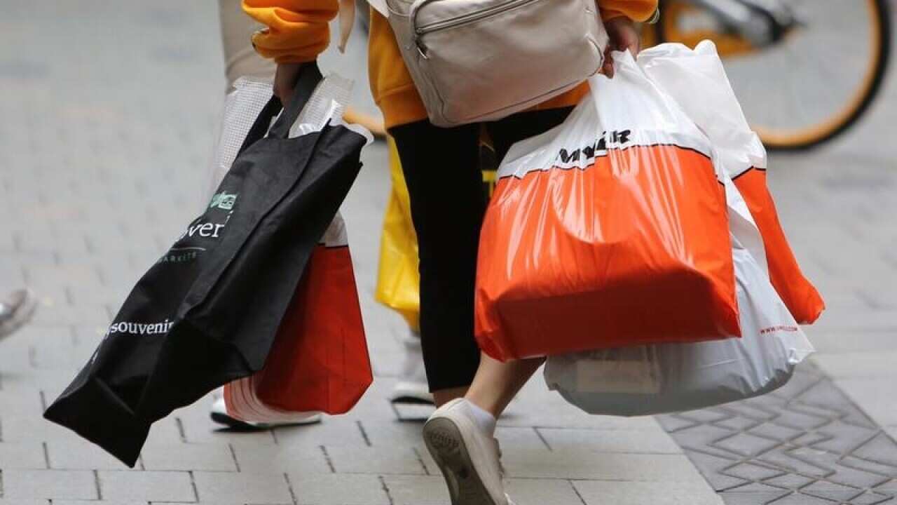 A shopper is seen carrying shopping bags.