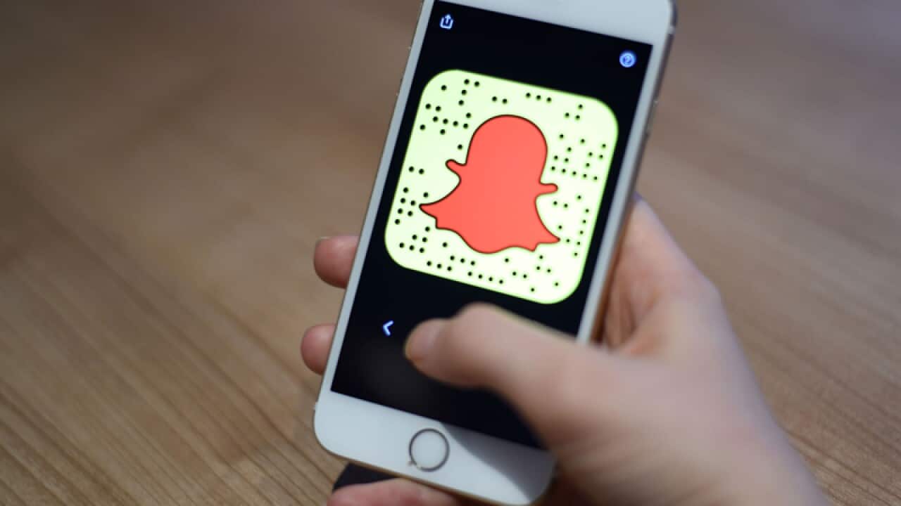 A general view of a woman holding a mobile phone with the Snapchat app