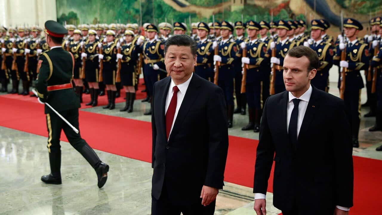 French President Emmanuel Macron (R) and his Chinese counterpart Xi Jinping (2-R) review honour guards during a welcome ceremony.