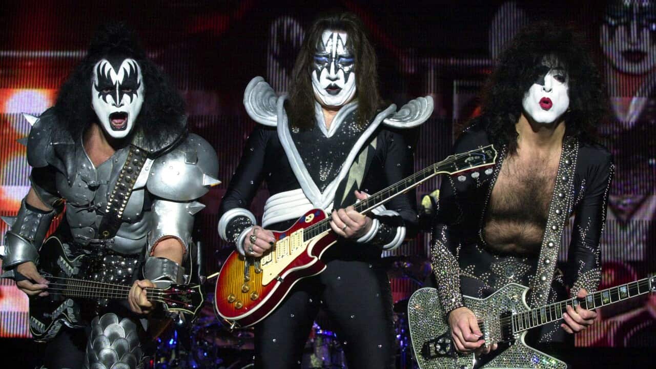 Three guitarists perform on a stage