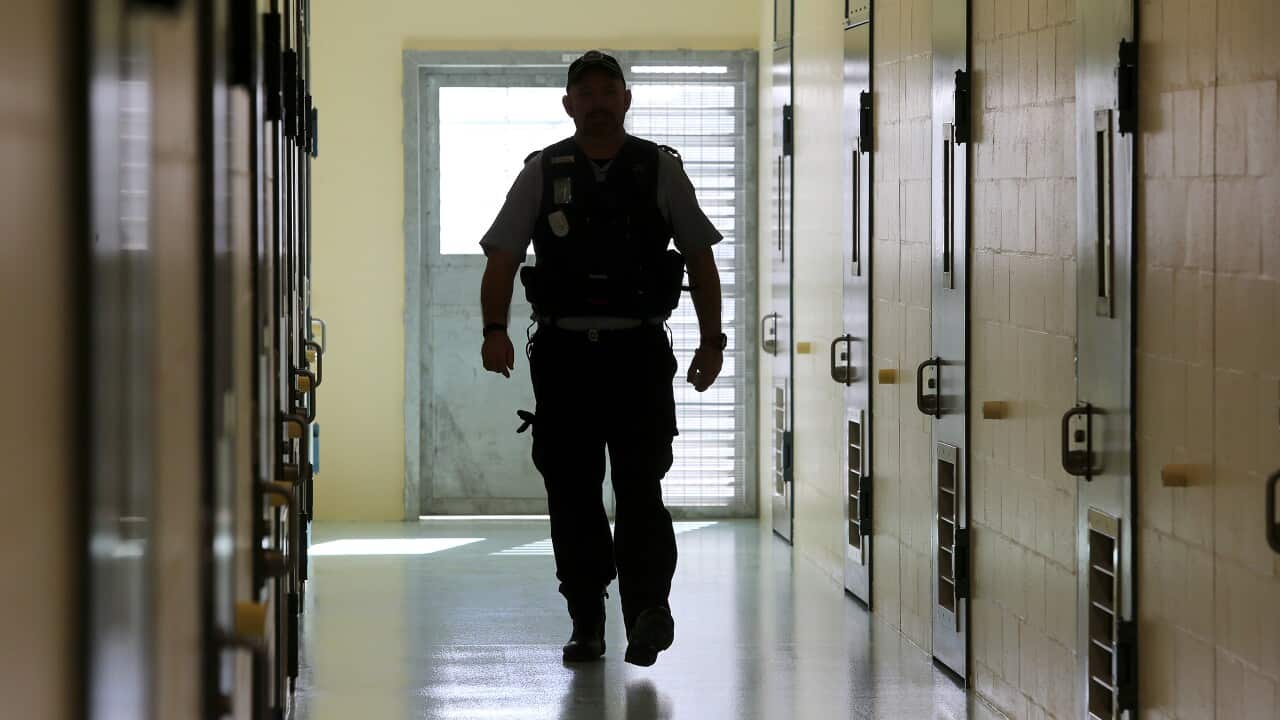 A correctional officer walks down a ward in a correctional centre.