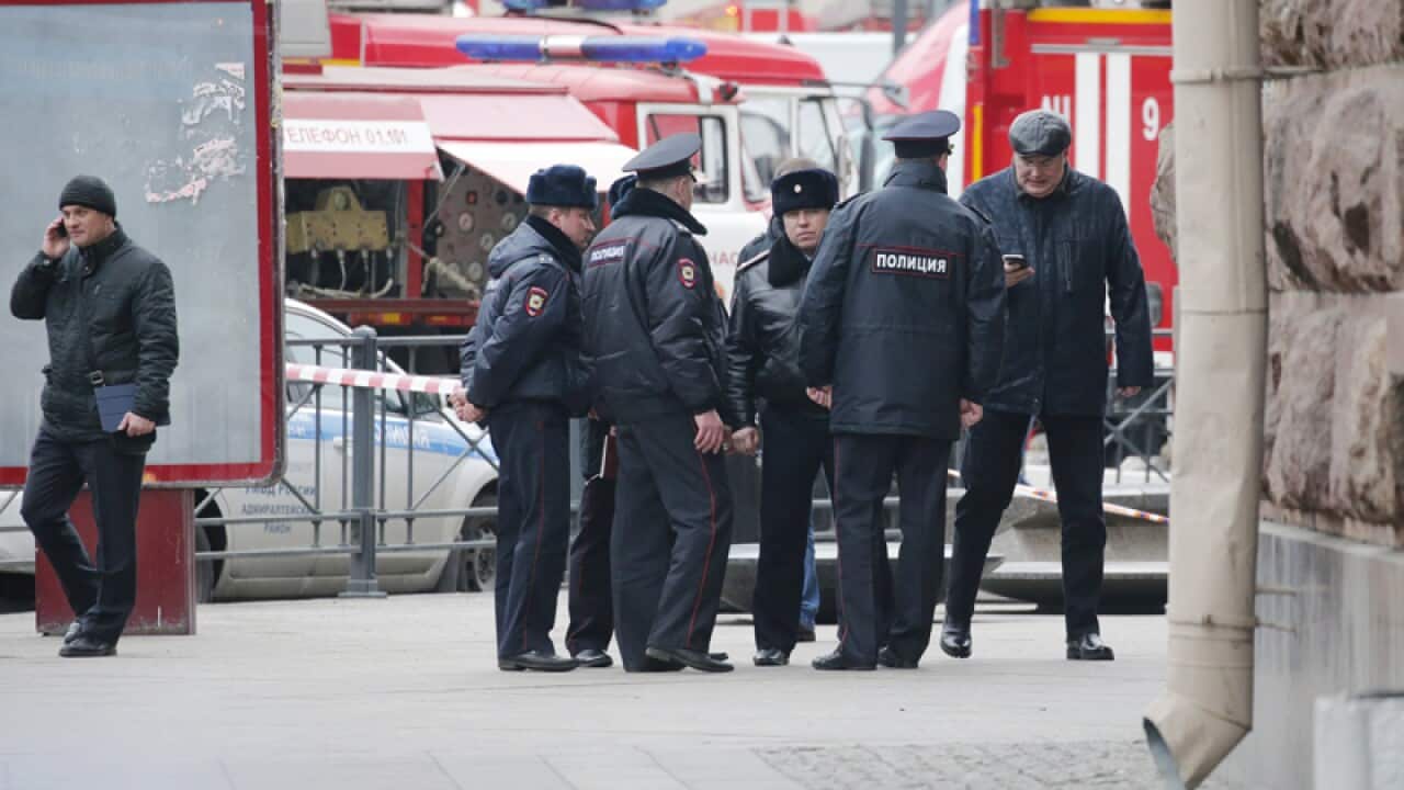 Police officers stand a Saint Petersburg metro after an explosion