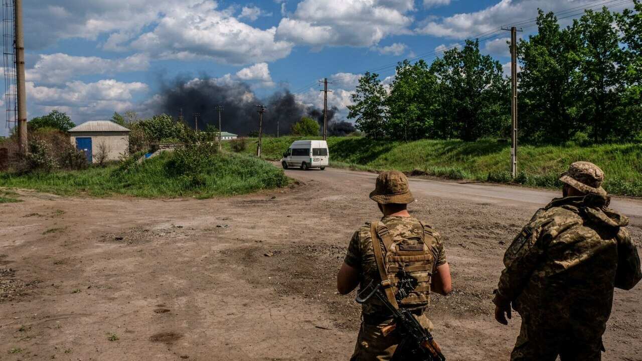 Troops look at smoke coming from an oil refinery in Lysychans'k (AAP)