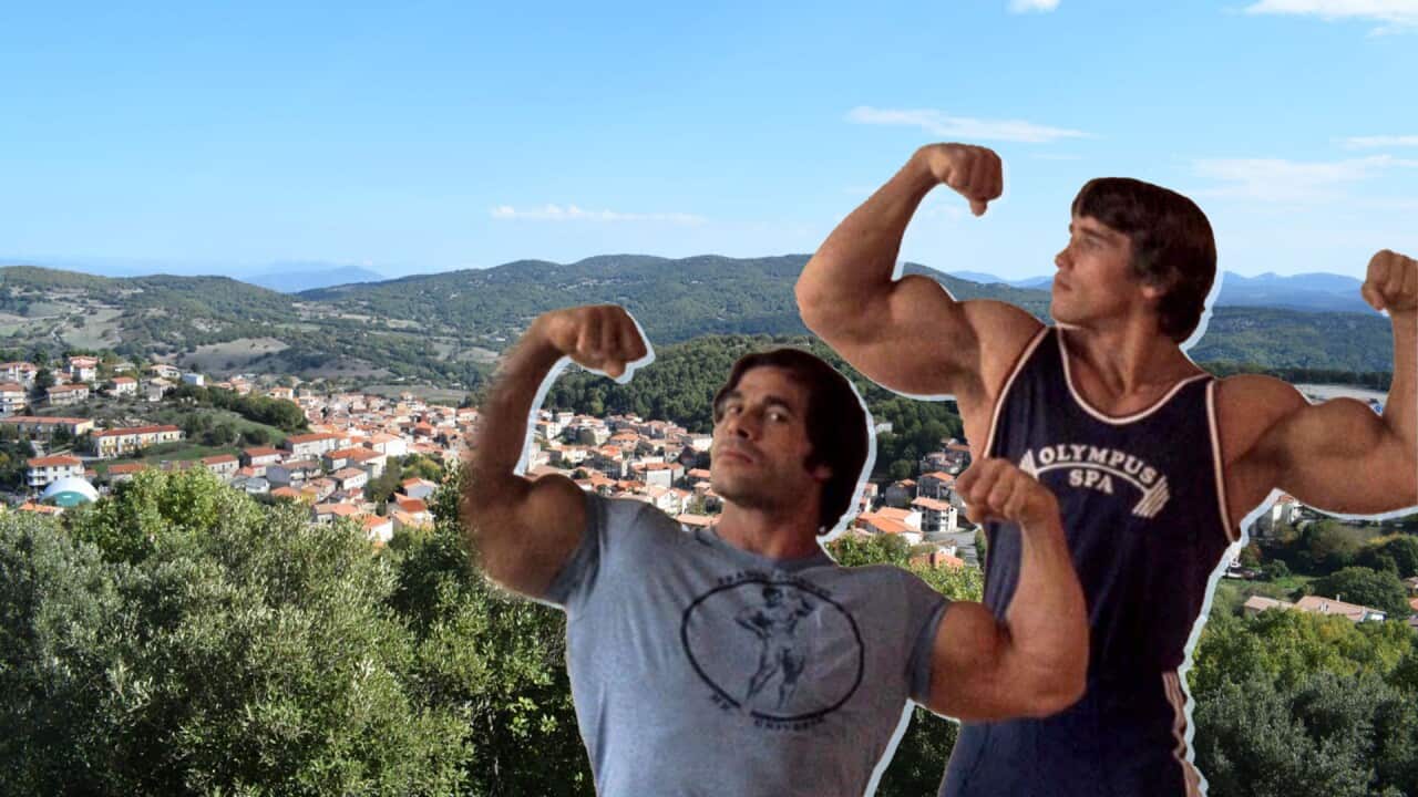 Two young bodybuilders flexing their biceps with a backdrop of a village surrounded by mountains