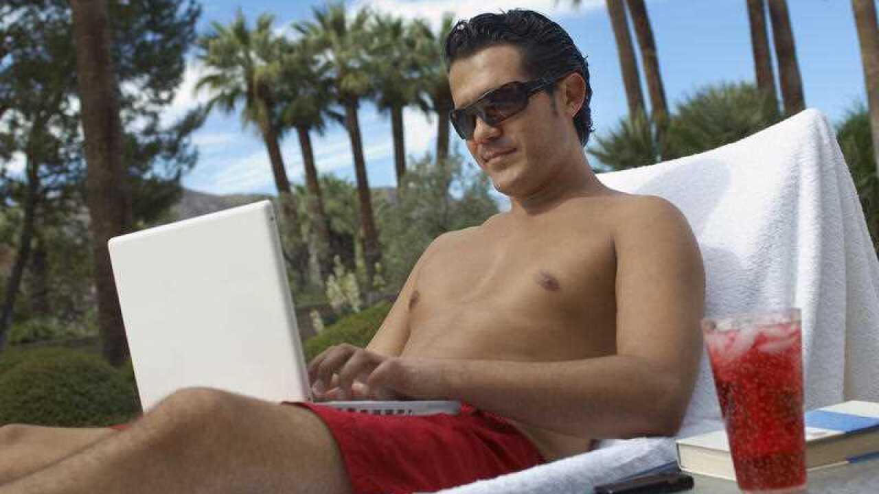Man sitting on deckchair using laptop