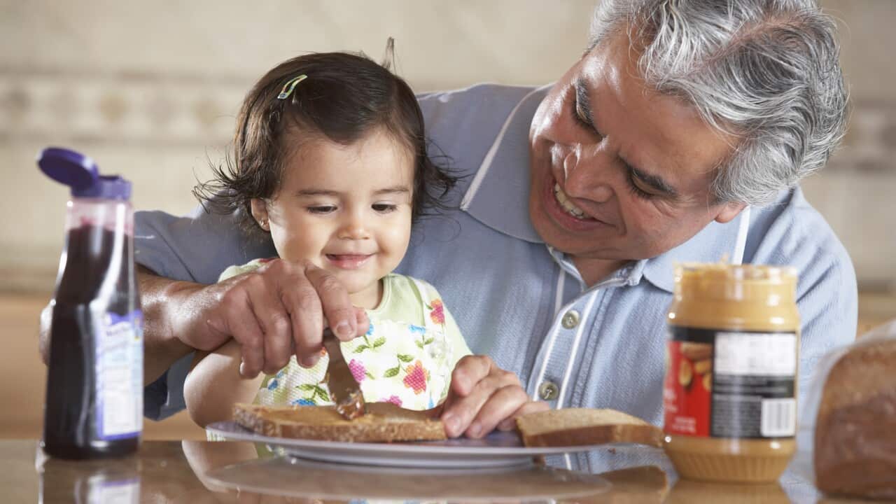 Grandfather helping granddaughter (12-15 months) make sandwich