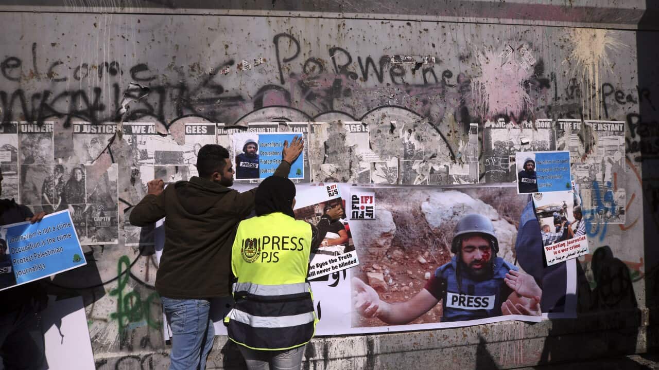 Palestinian journalist hang posters on a separation barrier in Bethlehem, West Bank, Sunday, Nov. 18, 2019, during a protest in support of a 35 year-old photographer Muath Amarneh. Amarneh's relatives say he has lost vision in one eye after apparently bei