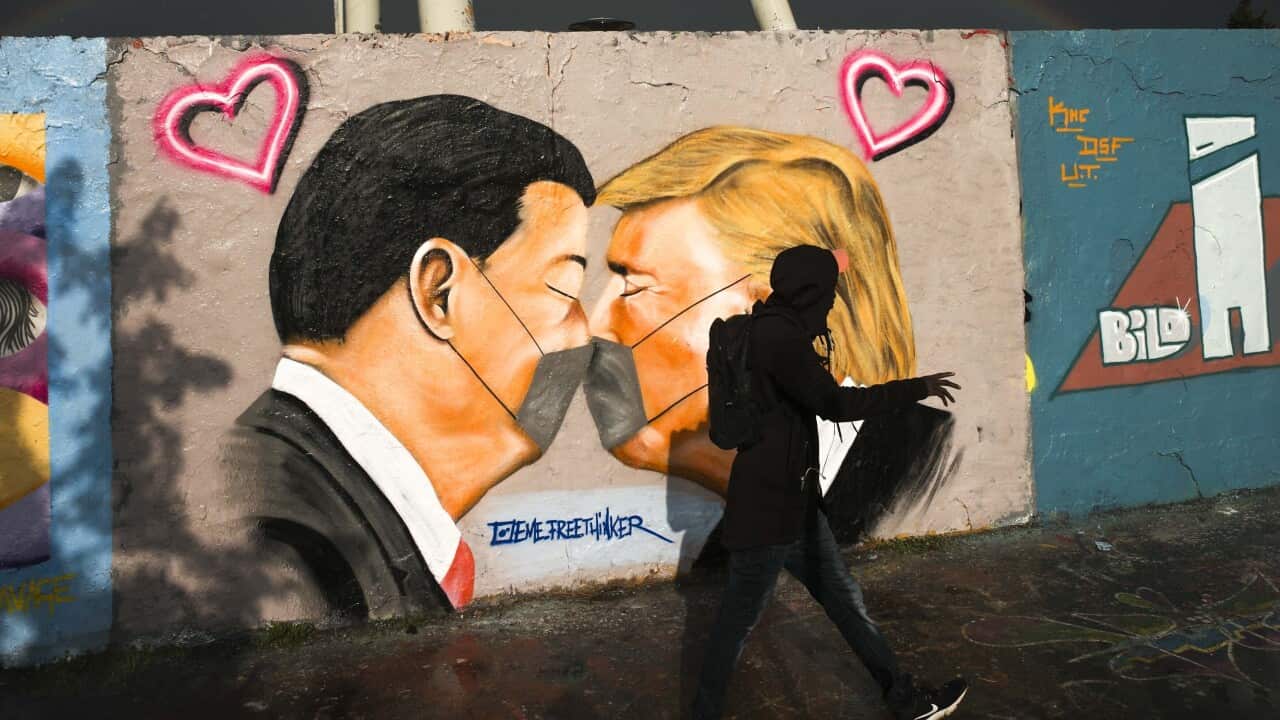 Graffiti depicting US President Trump, right, and China's President Xi Jinping kissing each other with face masks, displayed at a wall in Berlin, Germany.