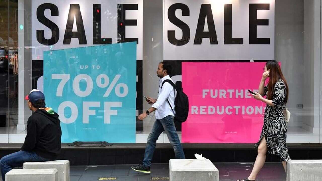 Pedestrians walk past a fashion store in Sydney