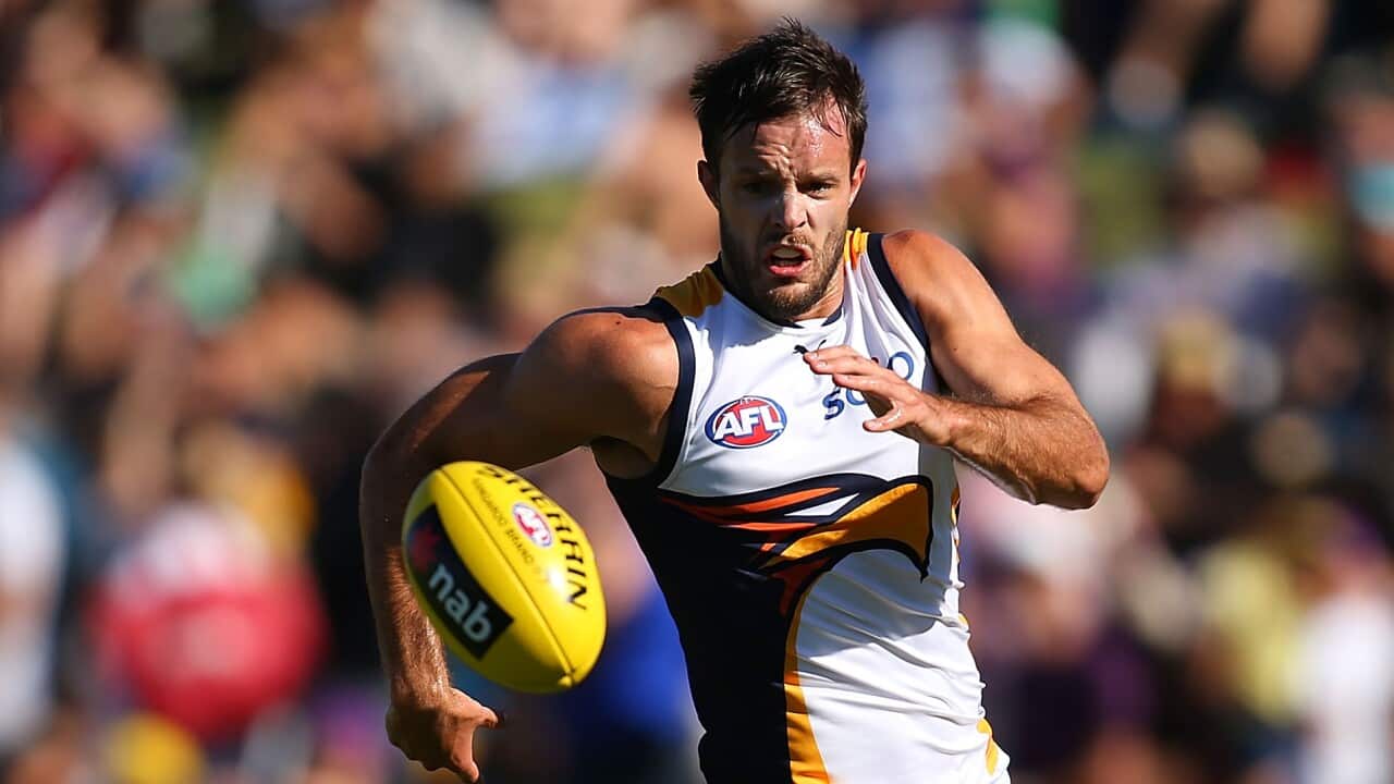 A football player runs onto the ball during a match as the crowd watches.