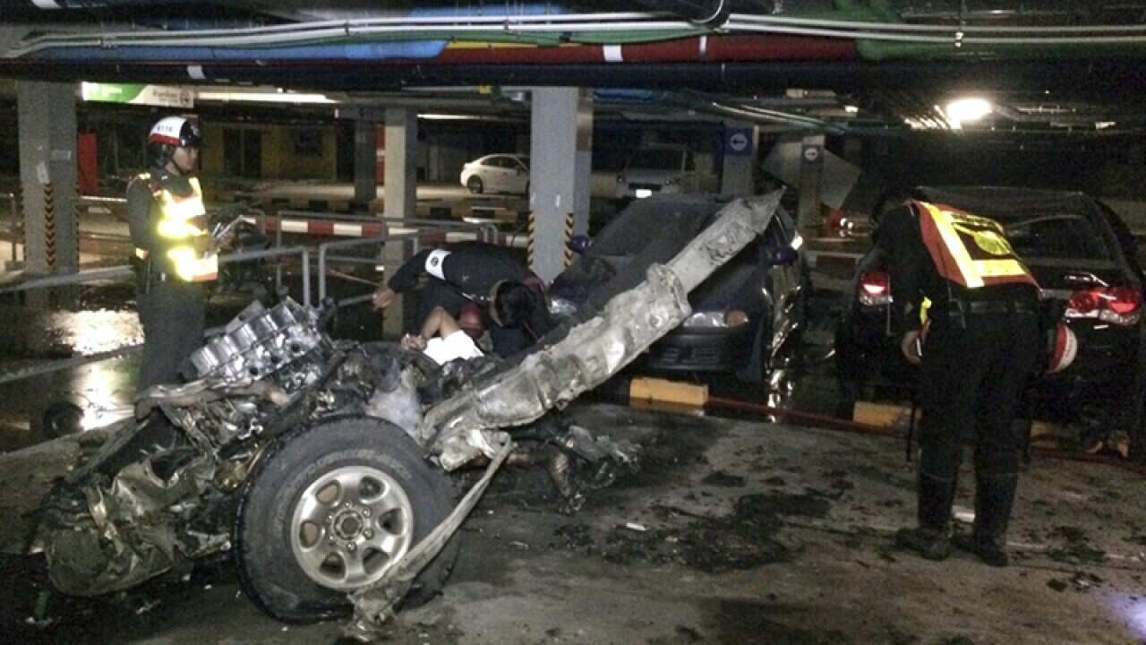 Thai police officers inspect the wreckage of a bomb blast
