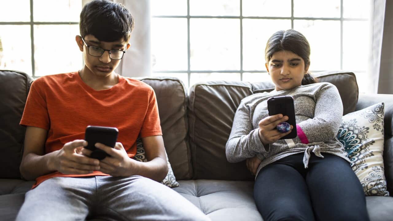 Brother and sister using smartphones at home
