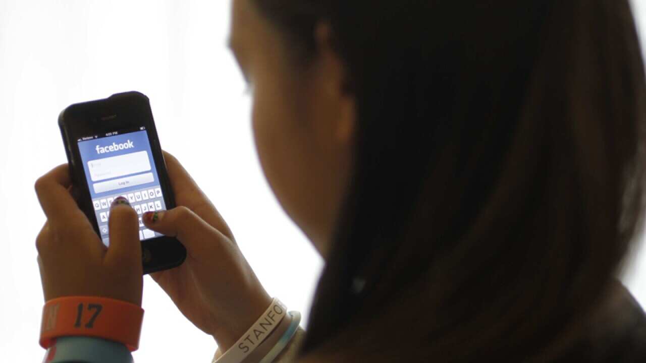 A girl logs into Facebook on her iPhone