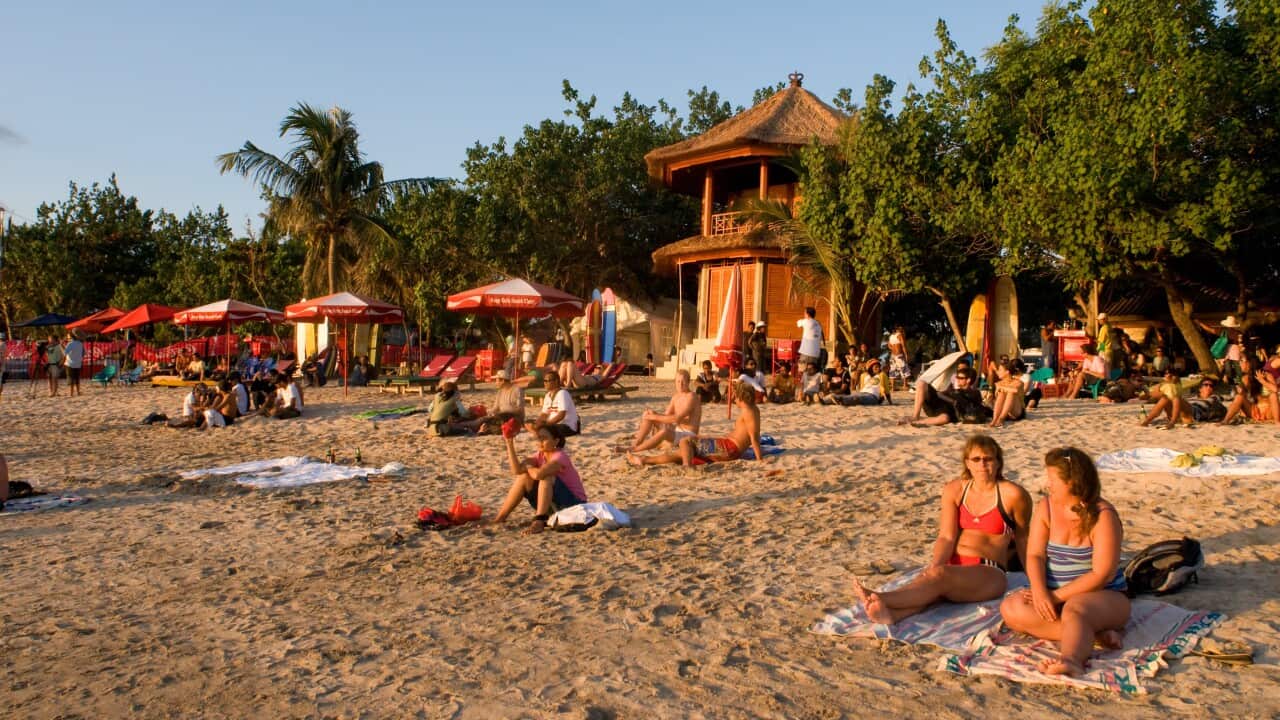 People sitting on towels on Canggu beach in Indonesia, enjoying the sunset.
