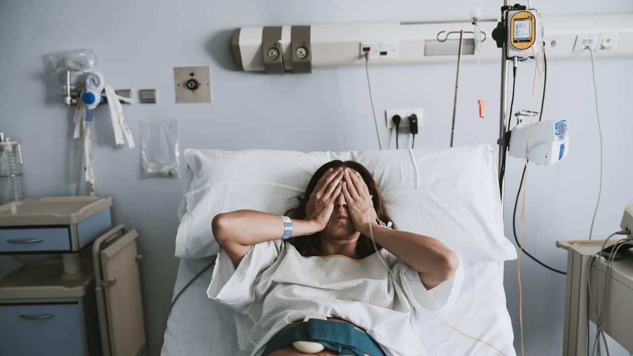 Stressed pregnant woman lying on bed in hospital
