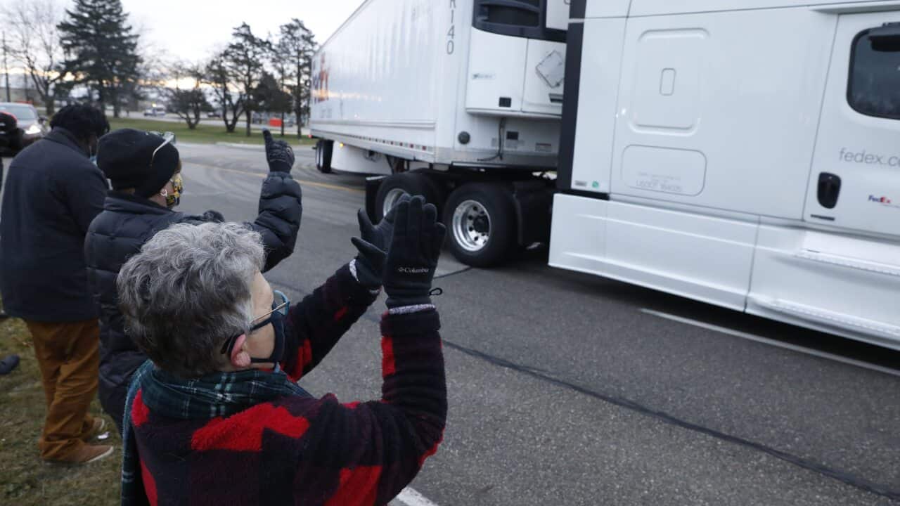 People cheer as trucks carrying the first shipment of the COVID-19 vaccine leaves Pfizer's Global Supply facility in Kalamazoo, Michigan on 13 December, 2020.