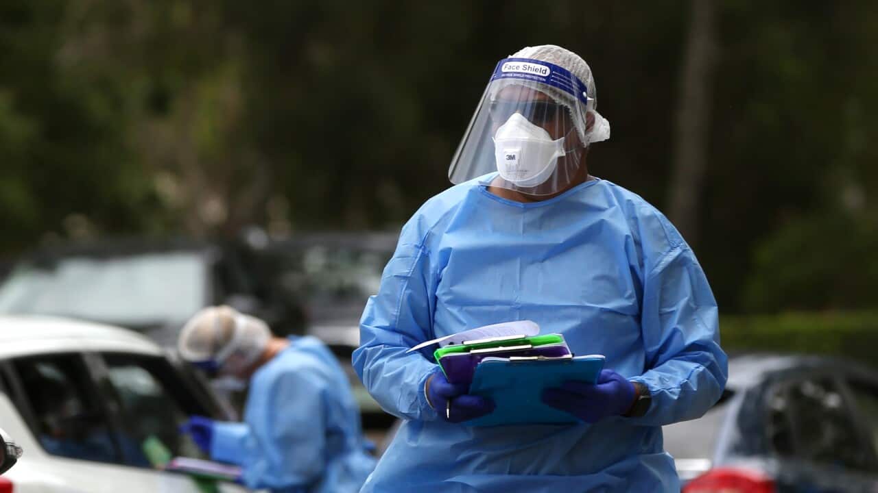 Staff are seen as members of the public queue for a COVID-19 test at a testing facility in Boondall, Brisbane.
