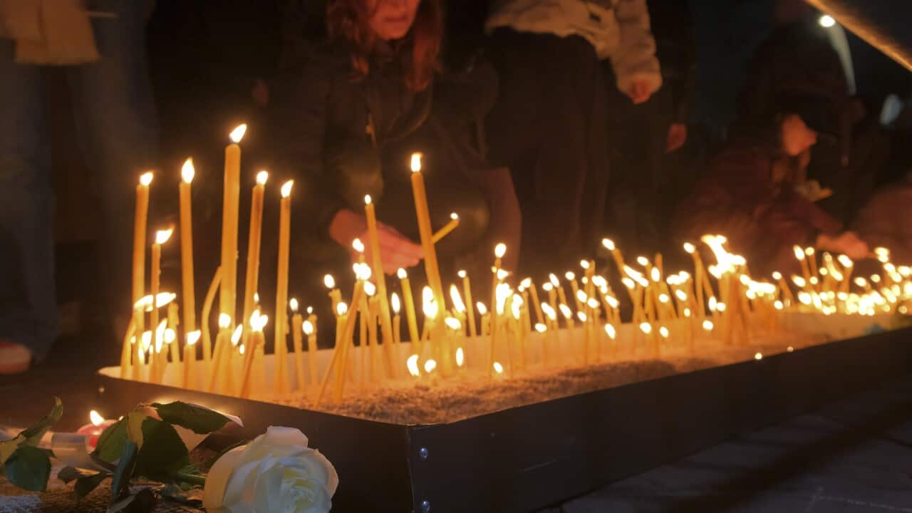 People kneeling and lighting candles.