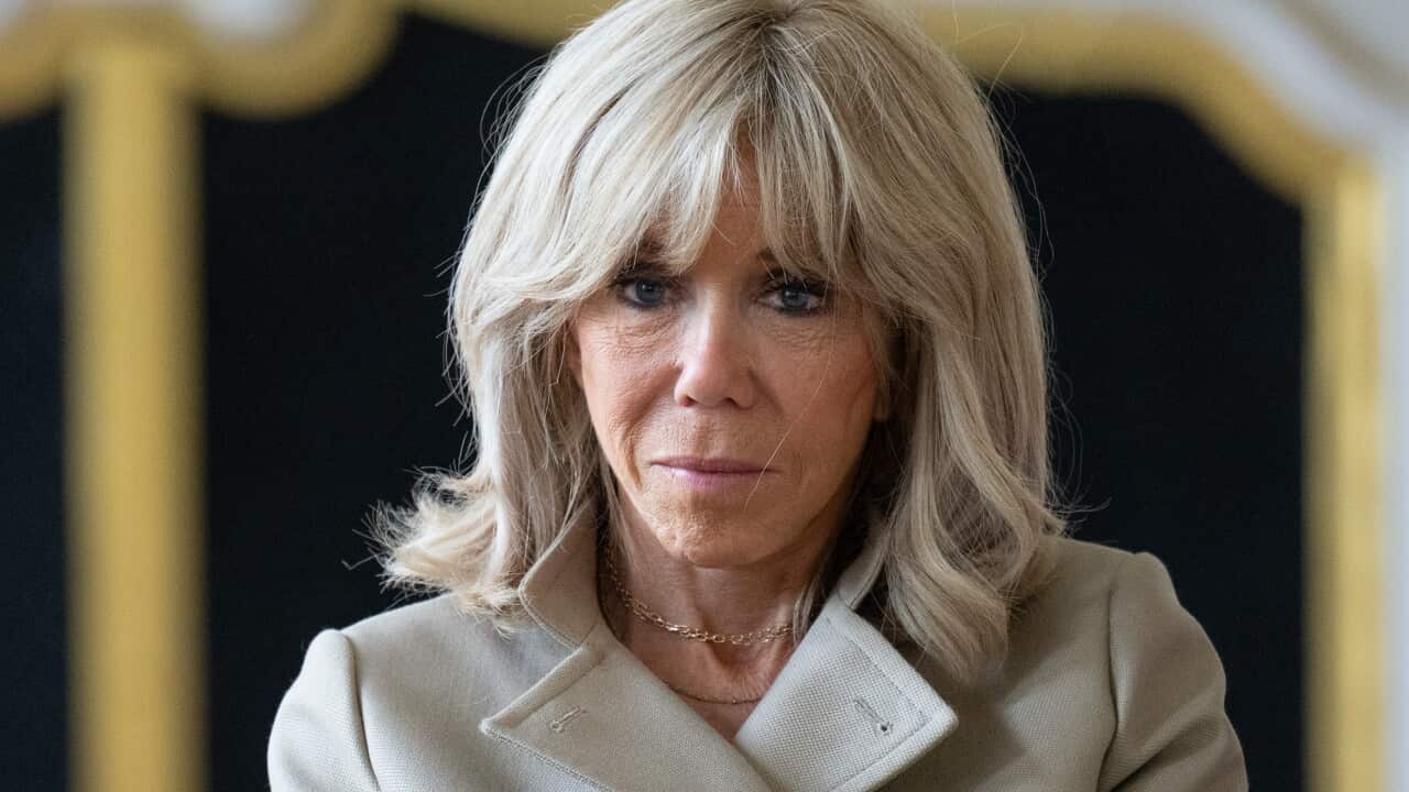 Brigitte Macron, wearing a light brown coat.