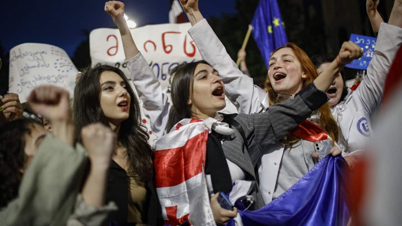 Female protesters wrapped in Georgia's flag hold up their firsts as they protest.
