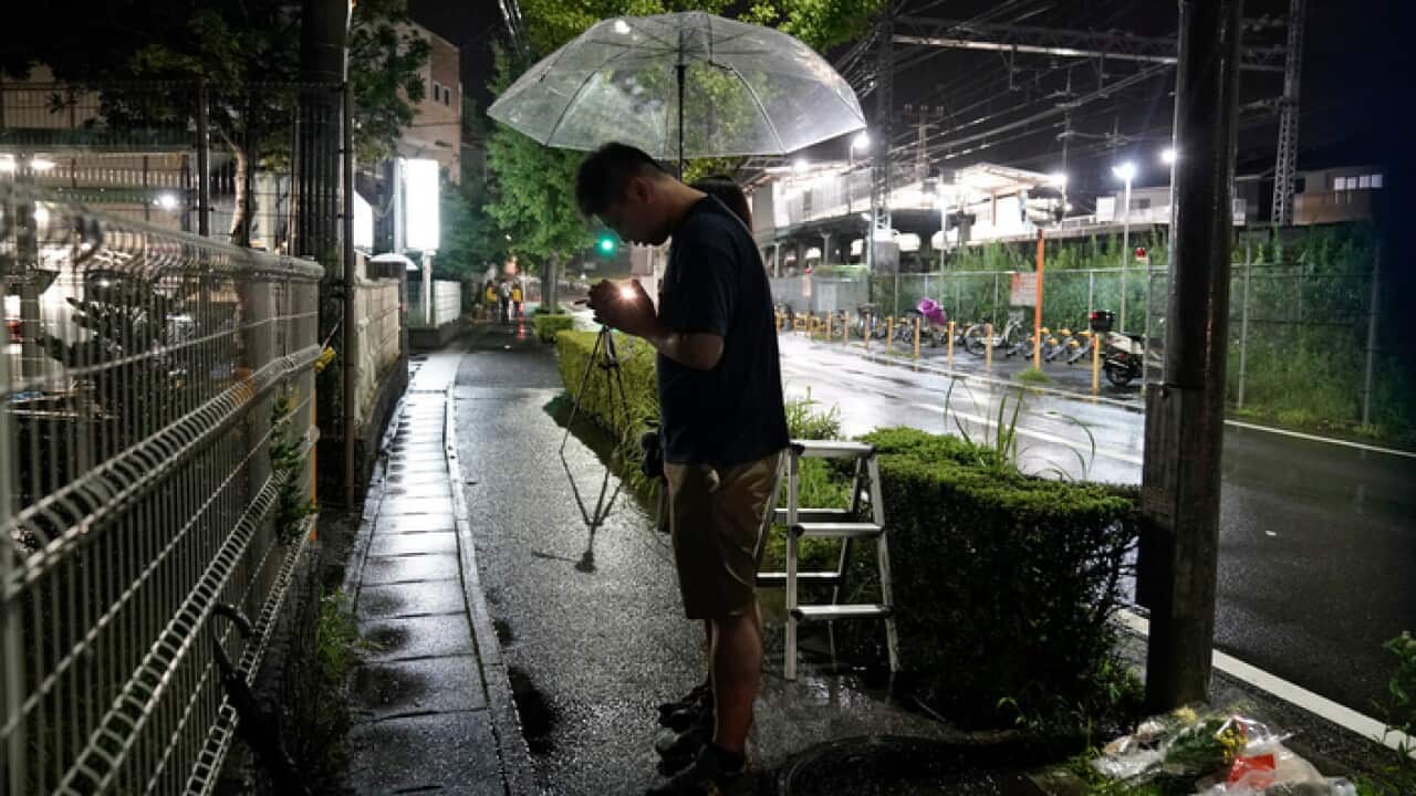 A couple prays after placing flowers near the Kyoto Animation building