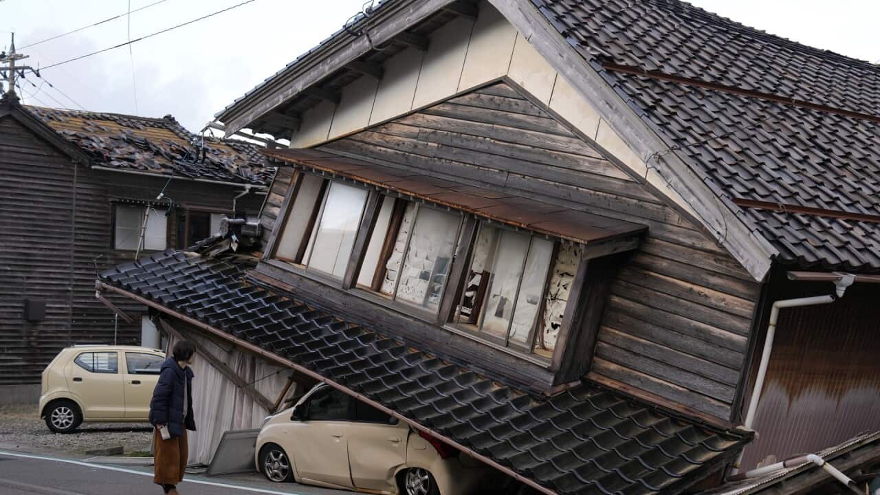 Local resident Kanae Yamazaki looks at the house where she grew up in Togi town, Noto Peninsula, Japan. The house has collapsed, crushing a car.