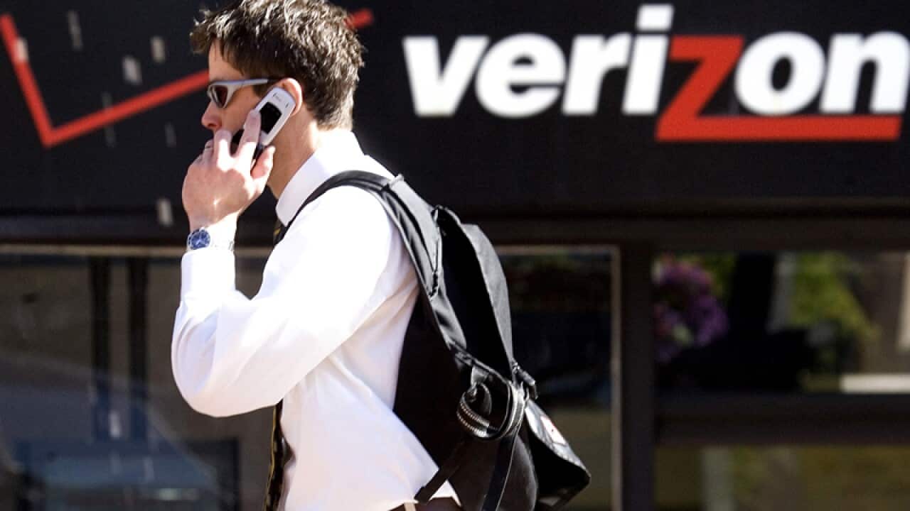 A man speaks on his phone as he walks past a Verizon store in Portland