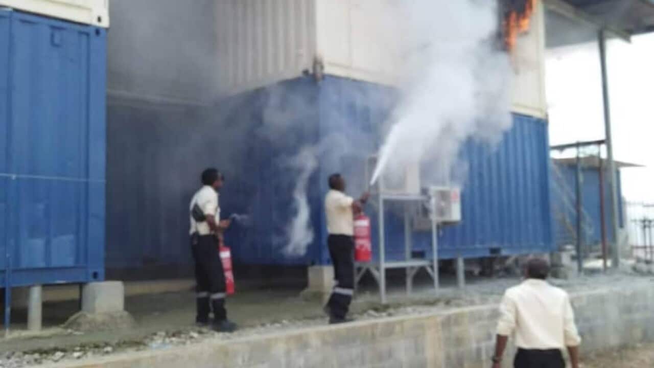 Police and immigration officers can be seen extinguishing the fire at the Manus Island compound.