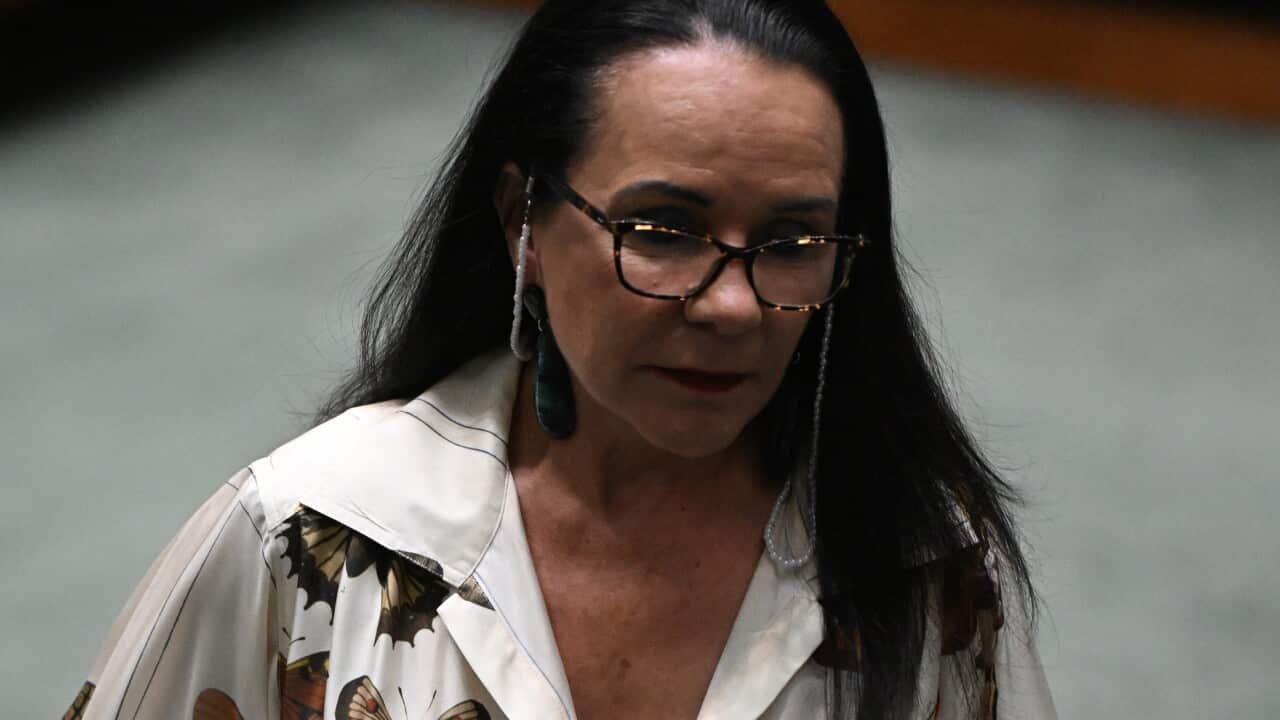 Linda Burney holding two folders while walking.