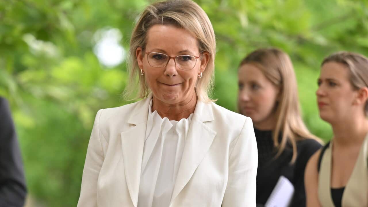 Opposition leader Sussan Ley, wearing white, is standing outside.