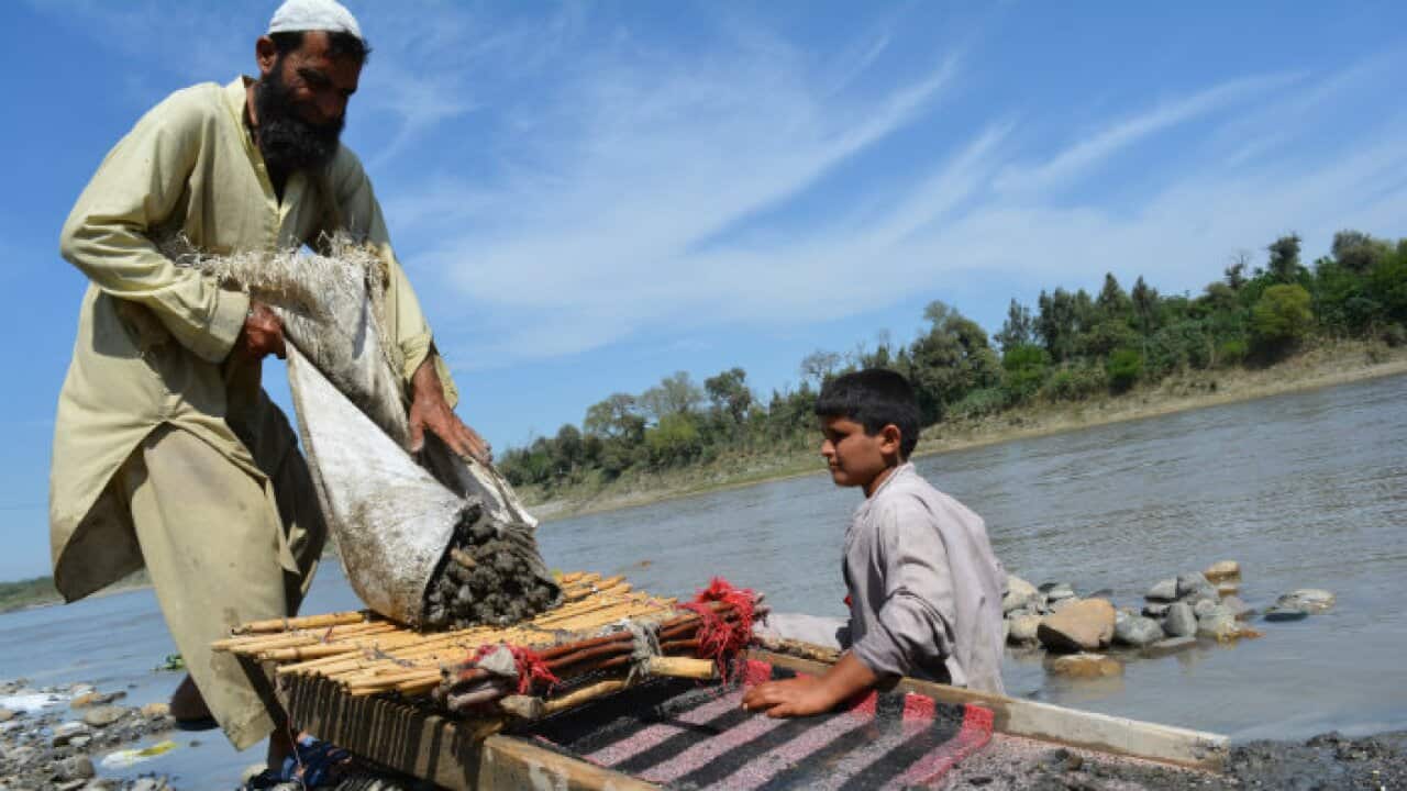 Father and son search for gold in Kabul river