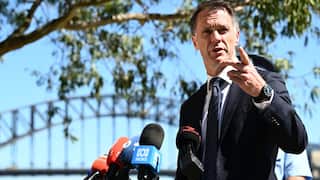 A middle-aged white man speaking a press conference, a bridge can be seen in the background