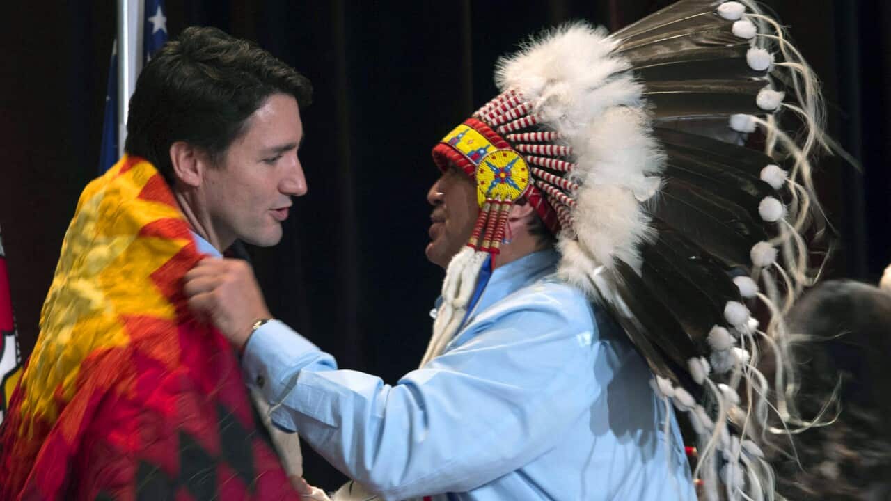 AFN National Chief Perry Bellegarde adjusts a blanket presented to Canada's Prime Minister Justin Trudeau following speeches at the Assembly of First Nations Special Chiefs Assembly in Gatineau, Quebec.