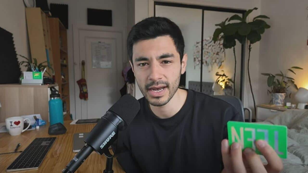 A man holds a gift card and speaks into a microphone
