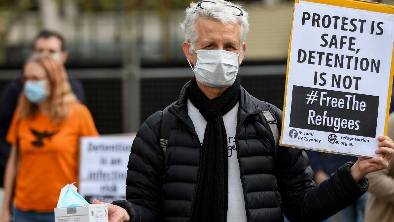 Protesters hold placards during a "Free The Refugees" rally at Sydney Town Hall in Sydney, Saturday, June 13, 2020. The Supreme Court on Thursday prohibited the protest from going ahead. (AAP Image/Bianca De Marchi) NO ARCHIVING