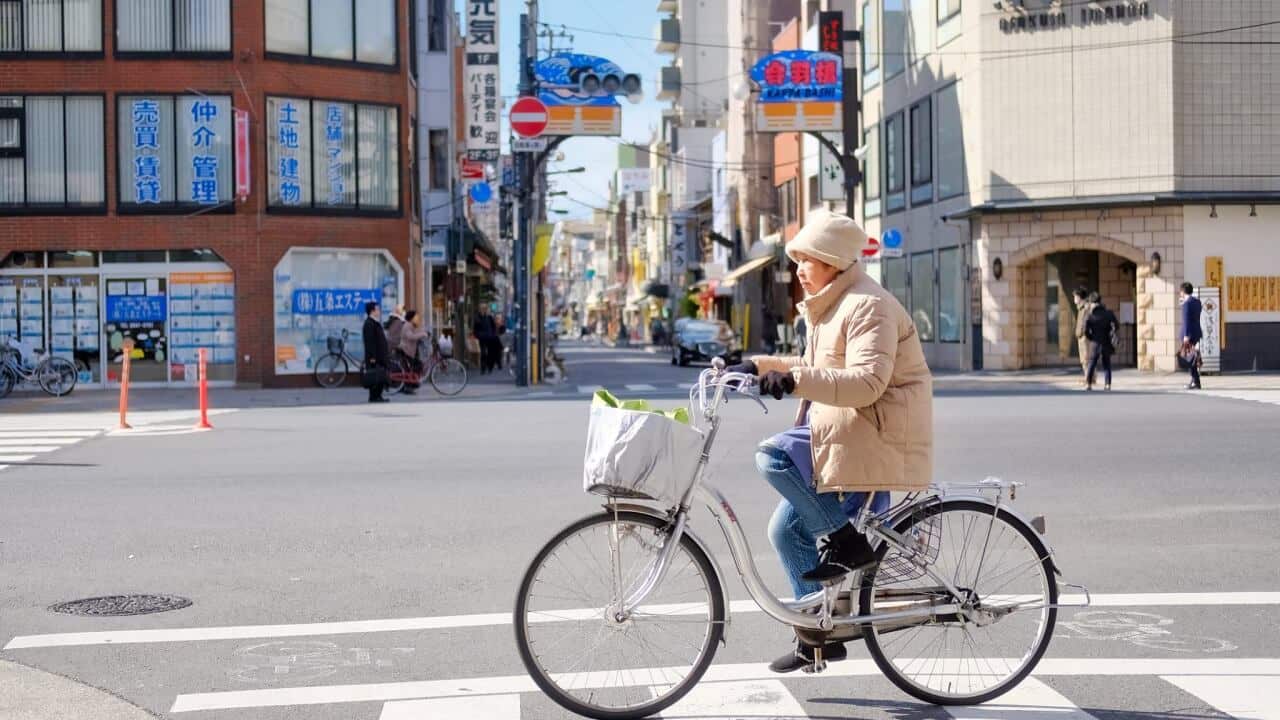 An old Japanese woman with her bicycle.