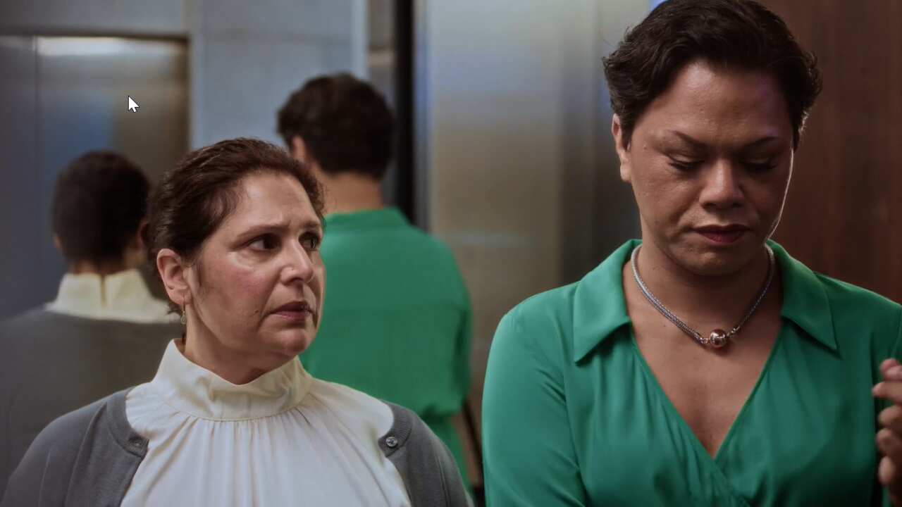 A woman stares warily at a person standing next to her in an elevator. 