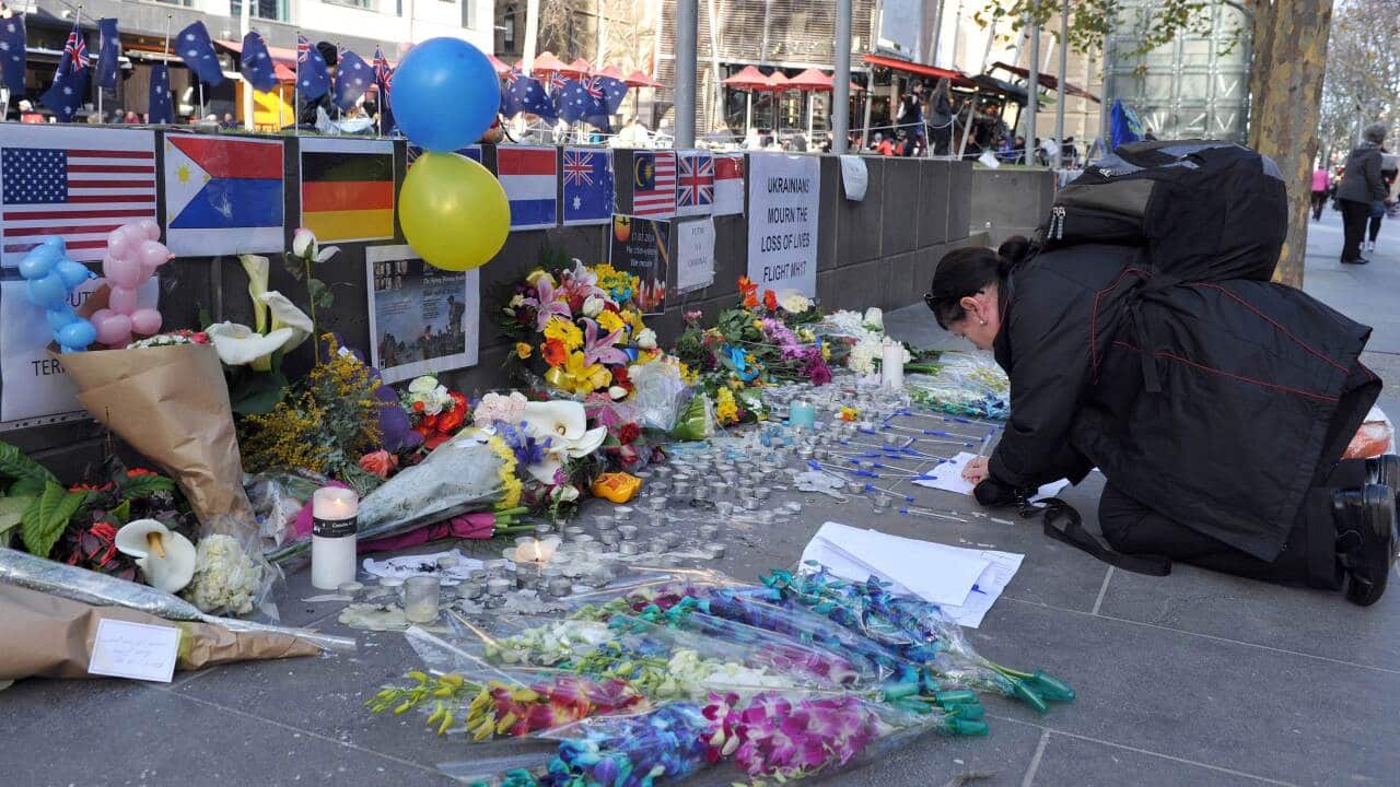 A woman paying her respects to those who lost their lives in the Malaysian Airlines MH17 catastrophe at a road side in Melbourne - AAP-001.jpg