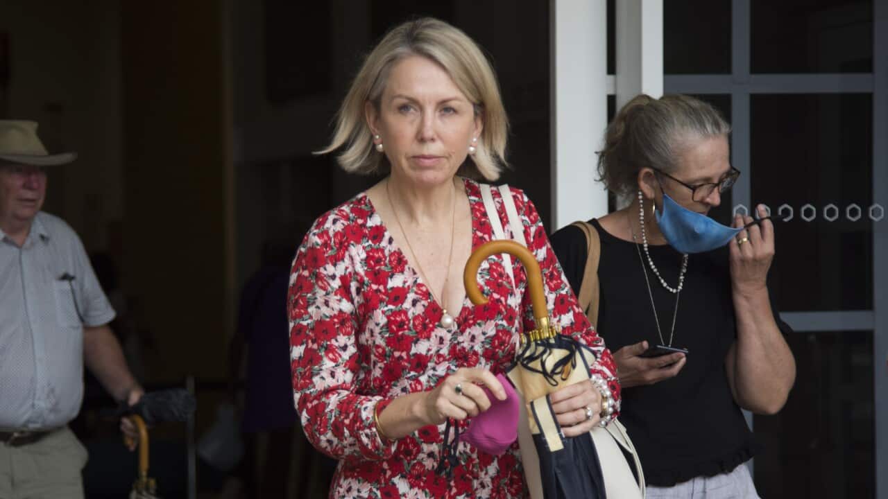 A blonde woman in a red floral dress leaves a court.