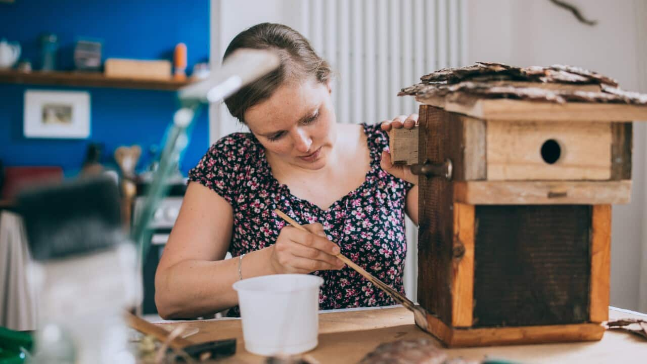 Woman painting a bird house.