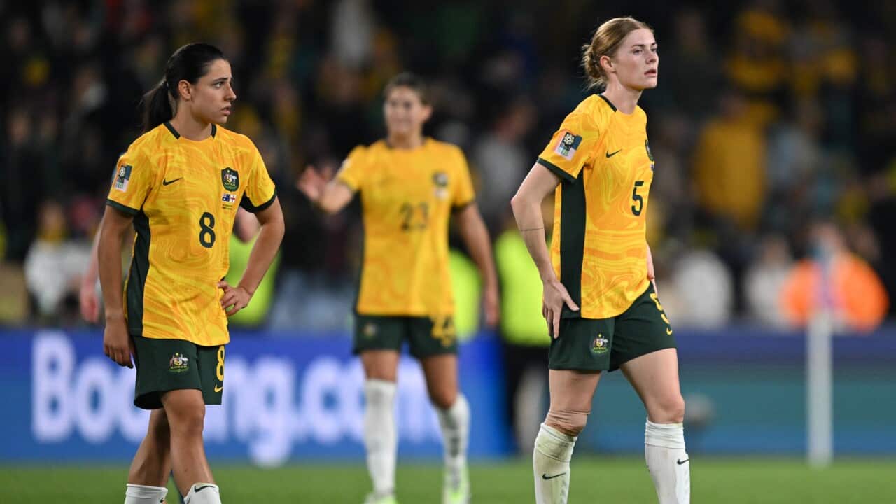 Two women with yellow football jerseys walking on the football field.