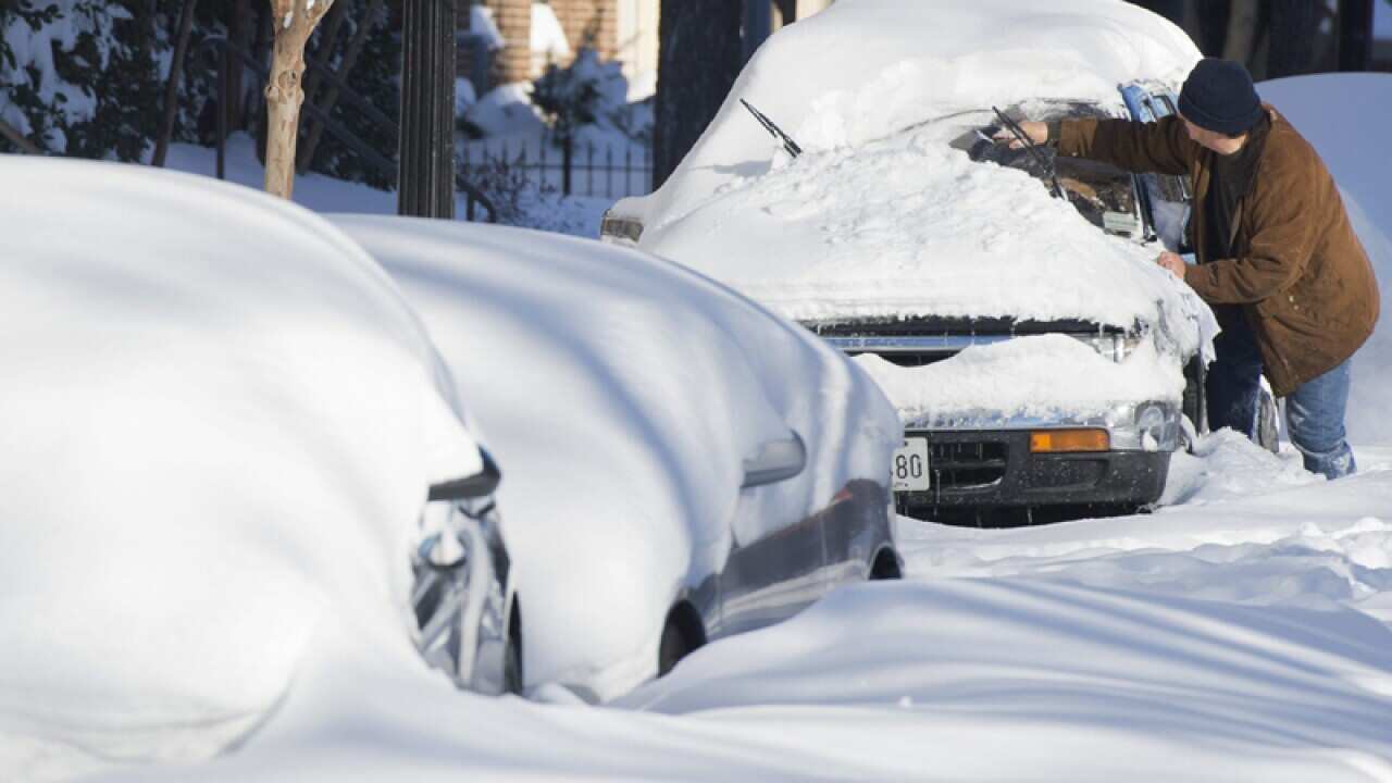 A man begins freeing a vehicle from snow.