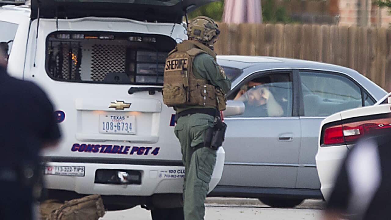 Law enforcement officers surround a shooting suspect in his car