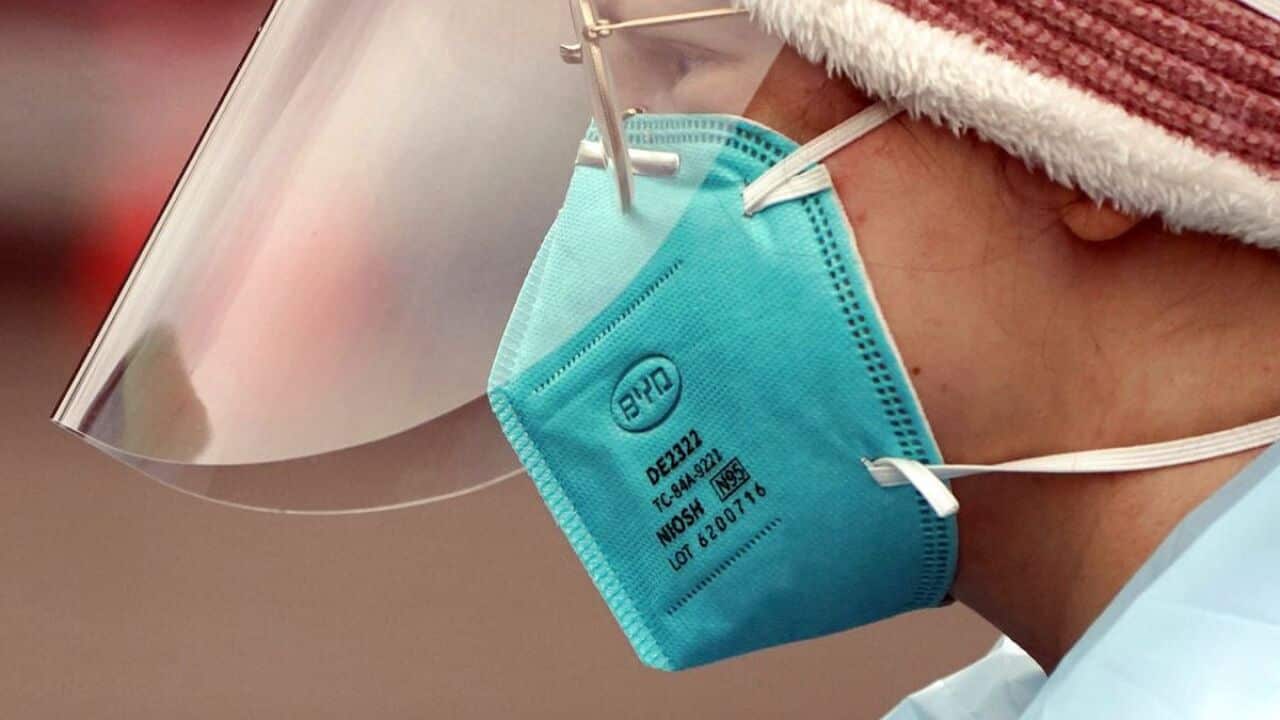 A medical assistant working at a drive-up COVID-19 testing clinic, wears an N95 mask