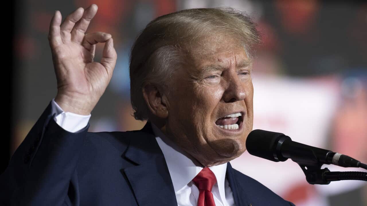 A man in a suit talking into a microphone