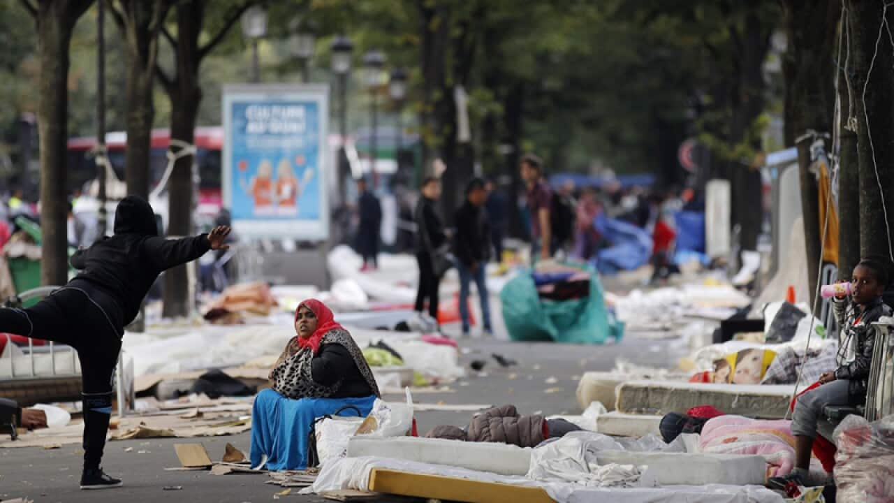 Migrants wait to be evacuated by French riot police