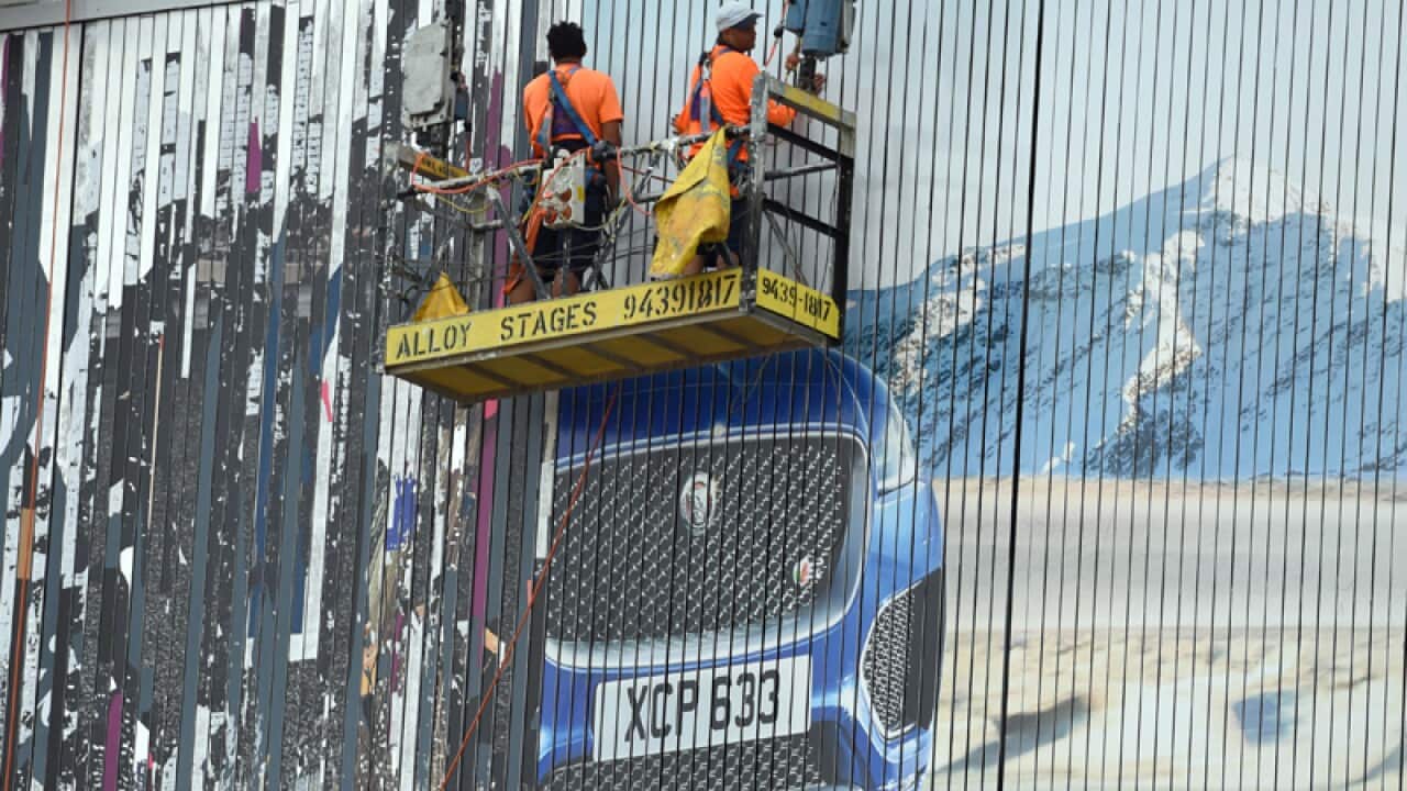 Workmen strip a prestige car advertisement