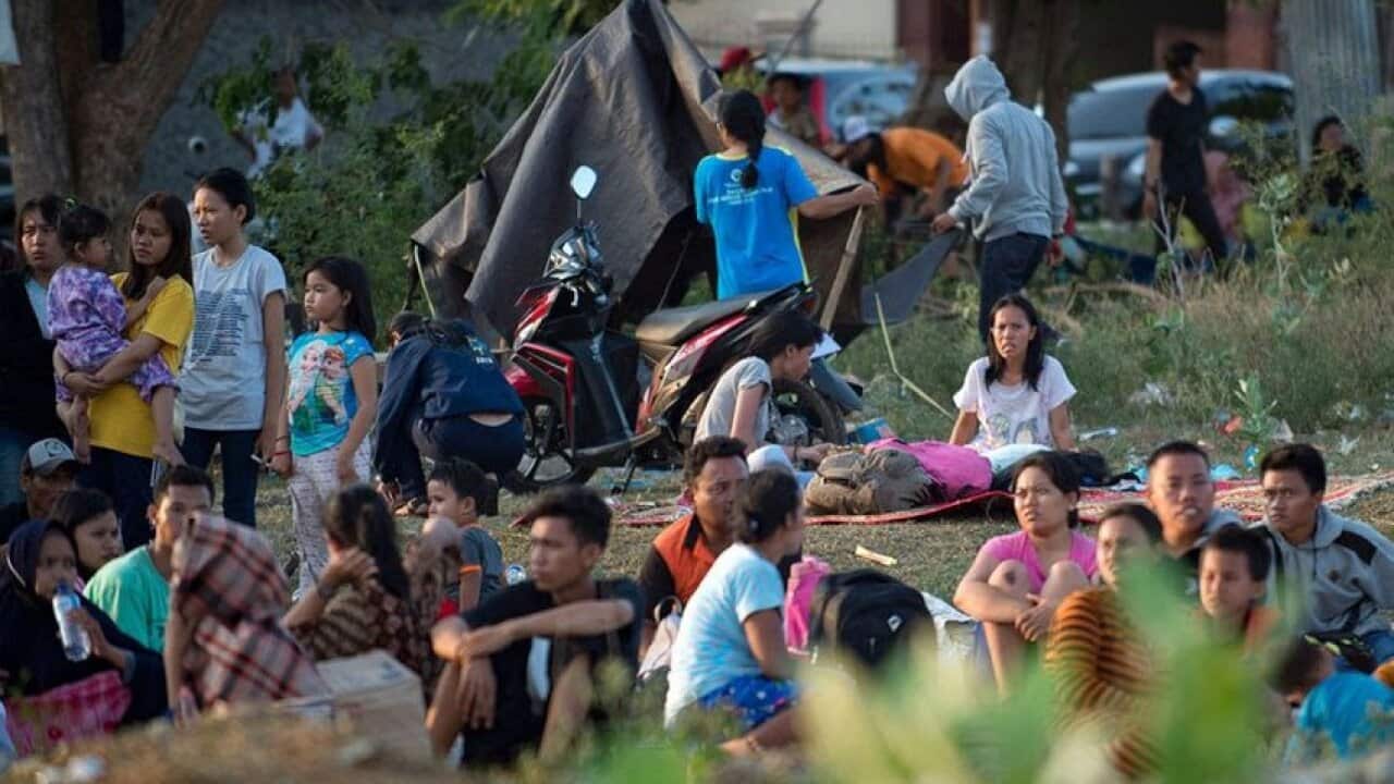 Residents sit in an open field rather than their homes in Palu on Sep 29, 2018, after a strong earthquake and tsunami struck the area.