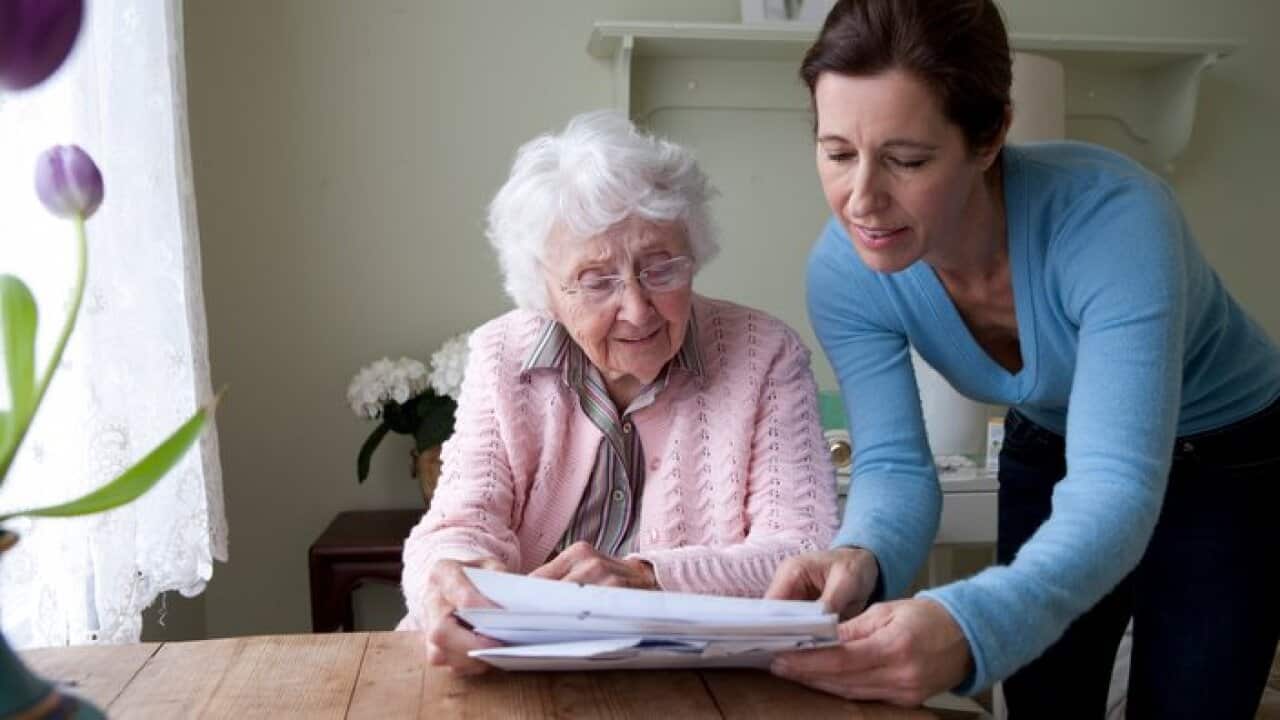 Woman reading to mother at table