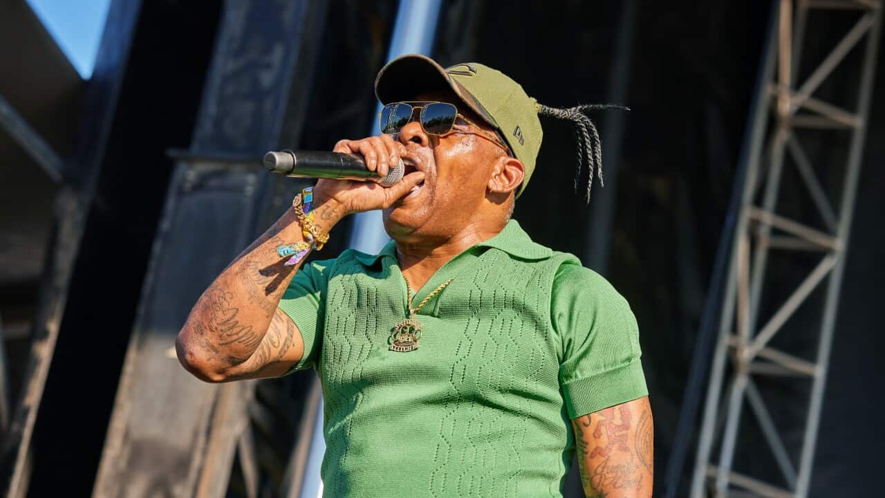 An African-American man raps into a microphone on stage
